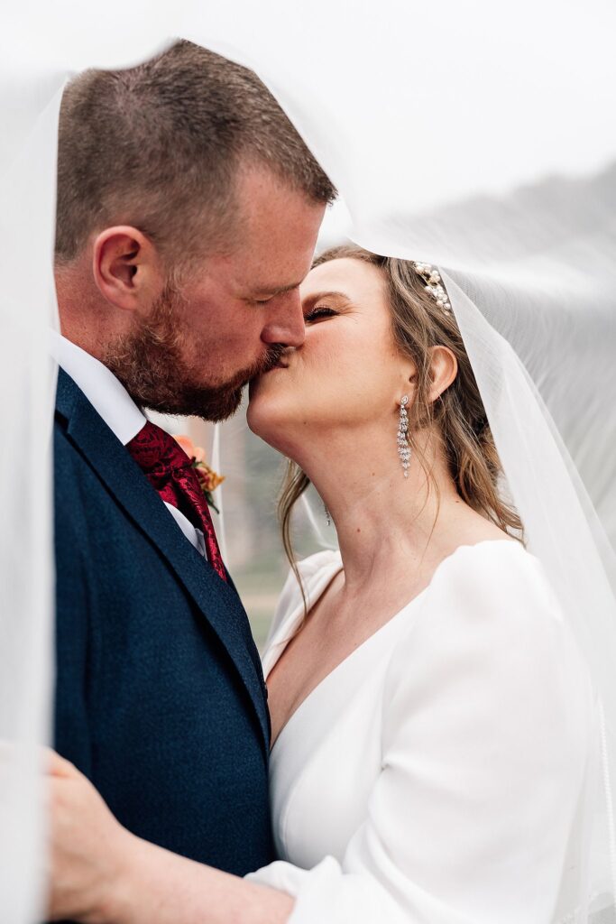 Newlyweds kiss under a beautiful veil