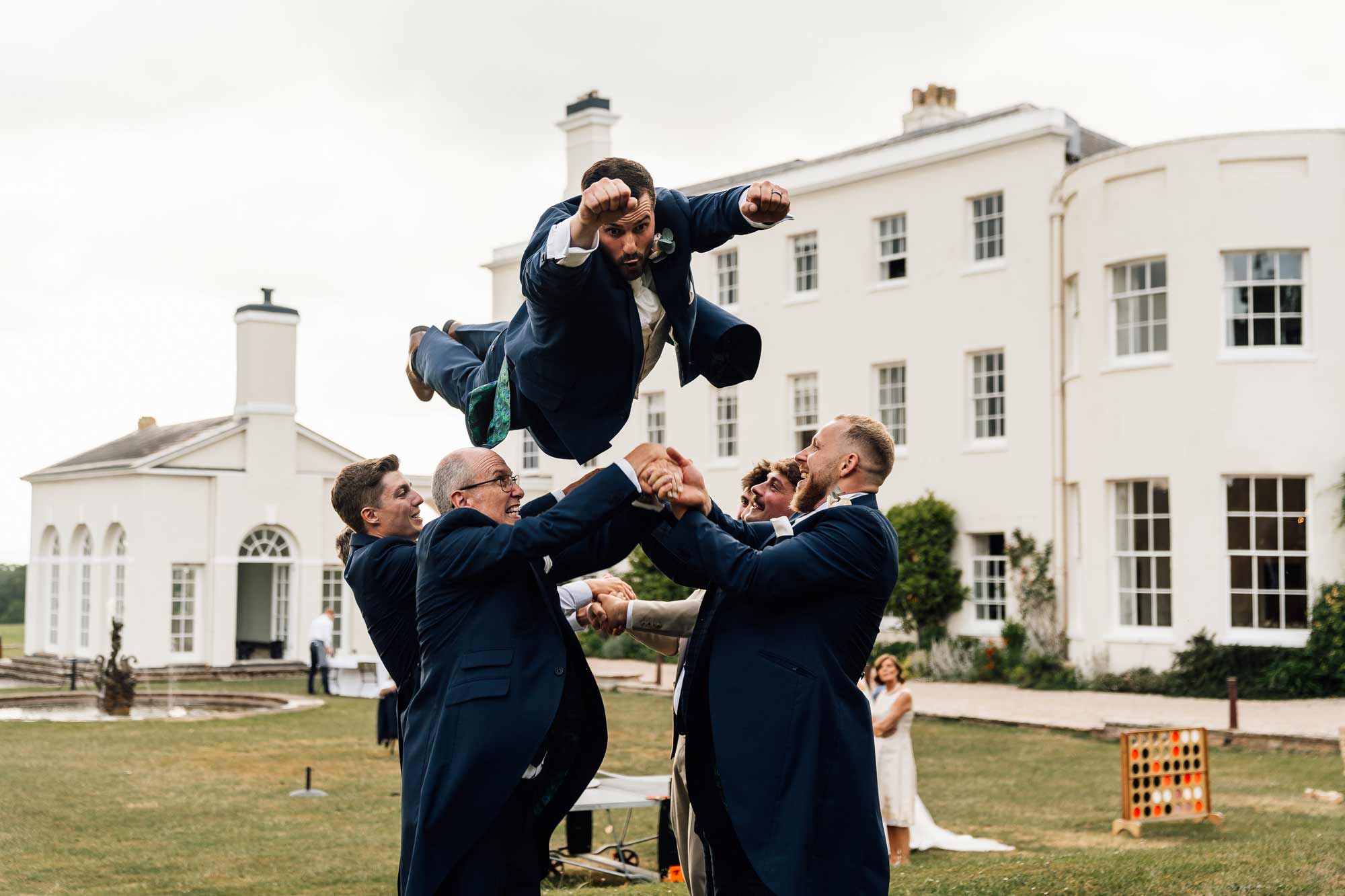 Groom being chucked up in the air at rockbeare manor wedding venue
